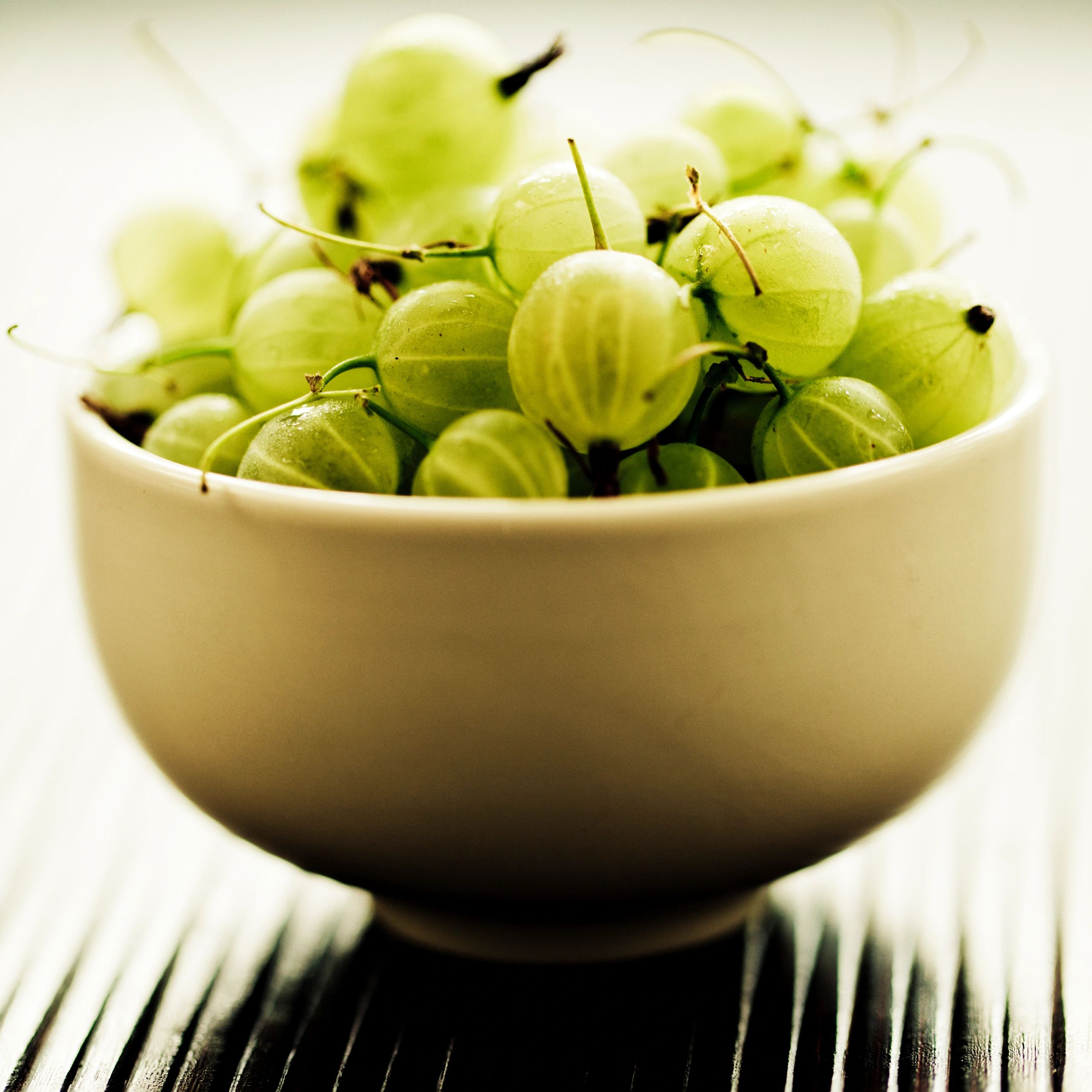 Close-up bowl of gooseberry-style fruit representing amla