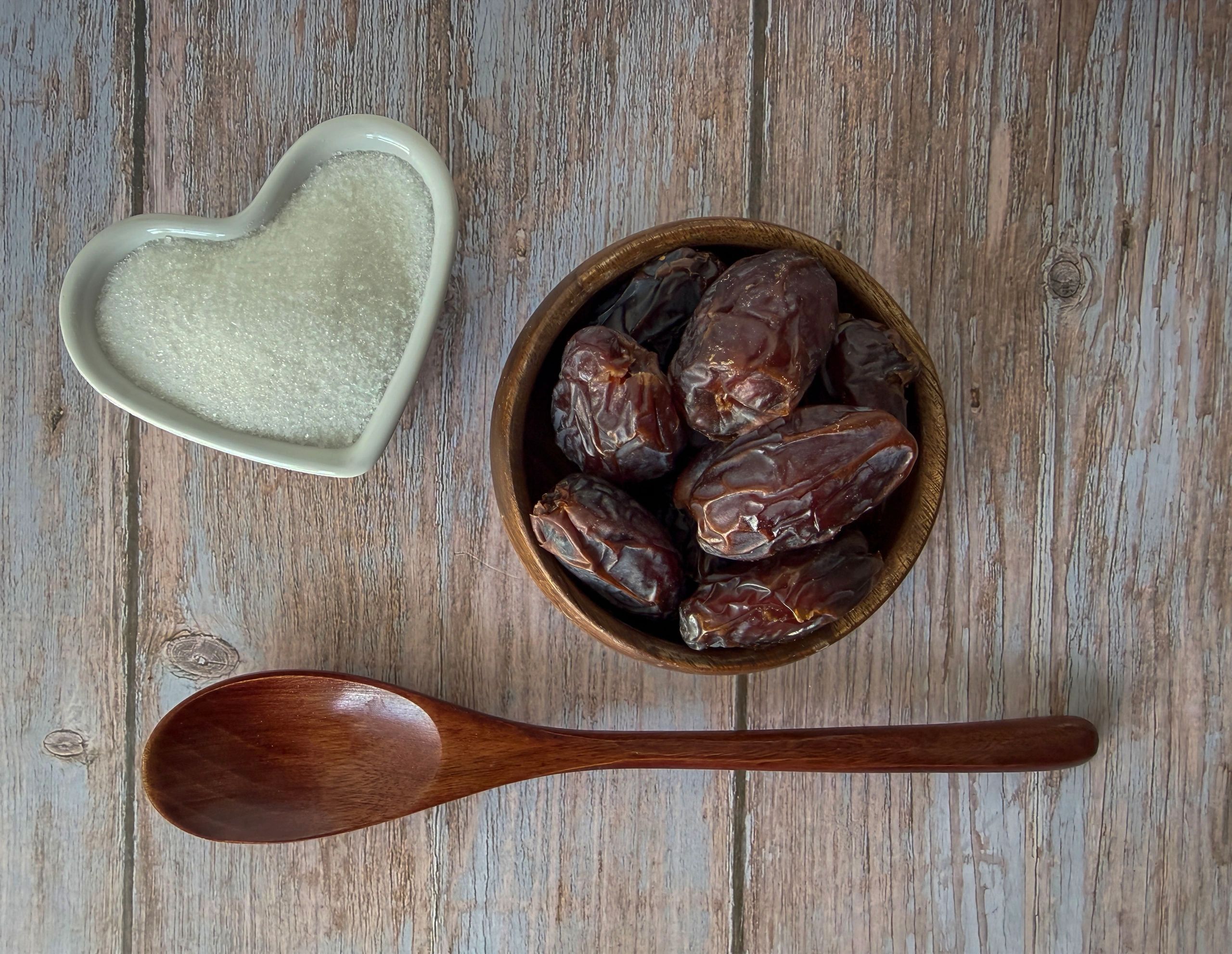 Wooden bowl filled with dried dates on a rustic table